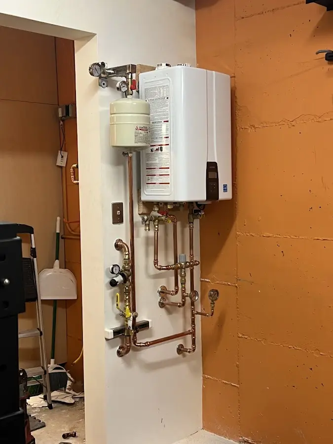Plumbing technician inspecting water heater connections in Waterboro